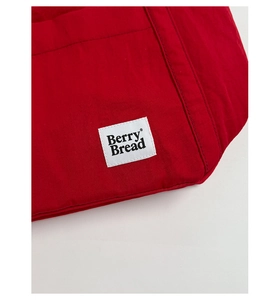 Detail of red fabric tote bag showing Berry Bread woven label and fine canvas texture
