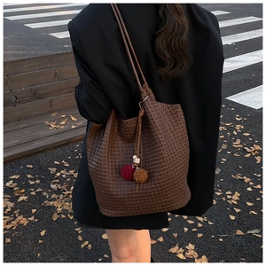 Detail of deep brown woven leather shoulder bag texture with autumn leaf on park bench
