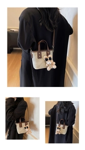 Detail van de beige mini bucket bag met leren rand en pluchen beer hanger
