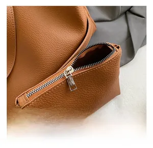 Detail showing the silver zipper hardware on the brown lychee pattern leather bag