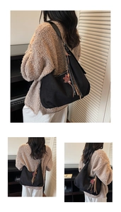 Detail of black suede hobo bag with tassel zipper and heart charm on a shoulder strap