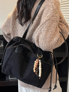 Minimalist black drawstring tote bag with long strap and wooden bead accessory