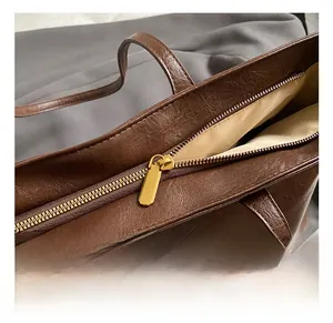 Close-up of golden zipper hardware on brown vintage leather tote with quality stitching