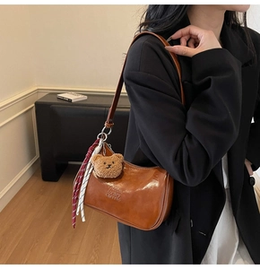 Detail of vintage brown half-moon bag with plush bear charm and Zichu brand embossing