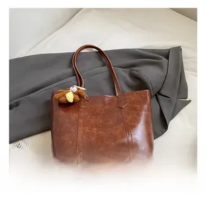 Detailed texture of brown PU leather tote bag featuring a cute yellow plush bear charm