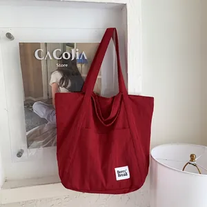 Detail of red canvas tote bag showing the Berry Bread woven label and front pocket