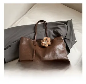 Close-up of deep coffee tote bag with vintage leather texture and cute plush bear charm