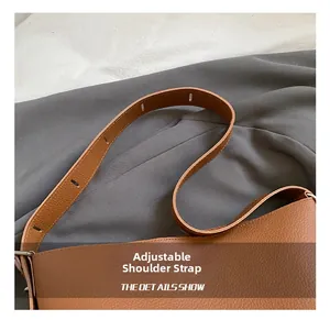 Detailed close-up of the adjustable leather shoulder strap on a brown pebbled crossbody bag