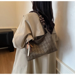 Detail of checkered brown shoulder bag with large beaded strap and boho tassel charms