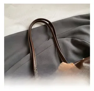 Macro detail of the reinforced leather shoulder strap on a brown vintage tote bag