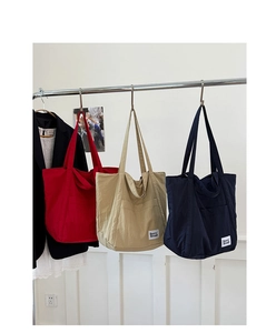 Detailed display of large canvas tote bags in red, beige, and navy with brand logo label