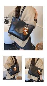 Detail of black faux leather tote bag with plush bear charm and brand logo