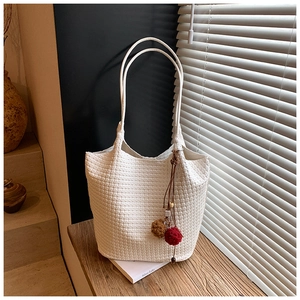 Close-up of a white woven tote bag on a wooden sill with soft window light and shadows