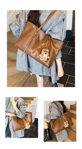 Close-up of dark brown tote bag with leather texture and cute teddy bear pendant charm