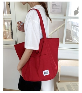 Detail of red canvas tote bag with Berry Bread label shown worn by a model
