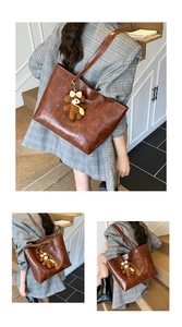 Detail of vintage brown tote bag with cute teddy bear charm and soft PU leather texture