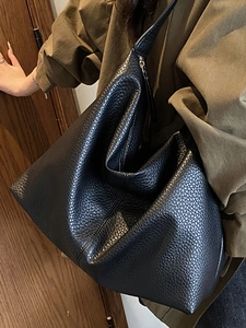 Minimalist large black pebbled leather tote bag with a crescent shape for daily commuting
