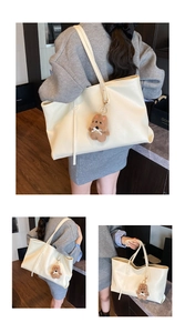Detail view of cream leather tote bag with brown teddy bear charm and textured finish