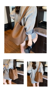 Detail showing the brown litchi grain leather texture and adjustable strap of the bucket bag