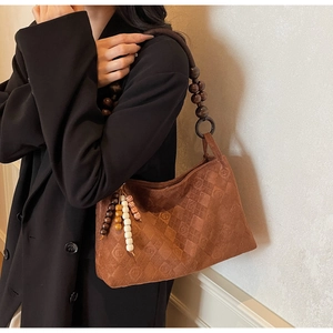 Detail of brown suede shoulder bag with wood bead strap and embossed diamond pattern