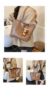 Detail of vintage brown PU leather tote bag with logo embossing and plush bear charm