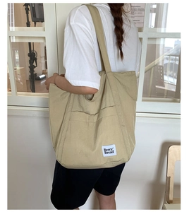 Detail of canvas tote bag showing large front pocket and white Berry Bread logo tag