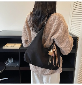 Detailed view of black suede hobo bag with star charm and brown tassels on model