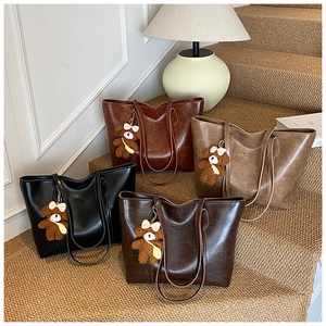 Detailed display of four vintage large capacity tote bags with plush bear pendants