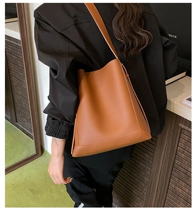 Detail of caramel brown lychee leather bucket bag with reinforced stitching and slim strap
