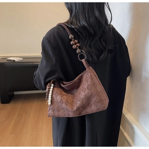Close-up of brown suede hobo bag with quilted patterns and ethnic wooden bead tassels