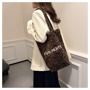 Detail of plush leopard print tote bag with 'FUN PARTY' text shown on a model