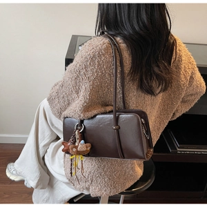 Détail d'un sac baguette vintage marron foncé avec breloques et fine bandoulière