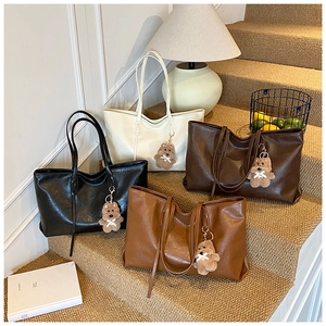 Detail of four colorful leather tote bags with cute dog charms and thin shoulder straps