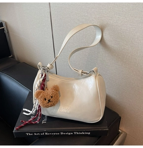 Detail view of cream vintage underarm bag with cute plush bear and Classic engraving