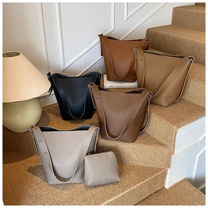 Litchi texture leather bucket bags in black, caramel, camel and grey on steps