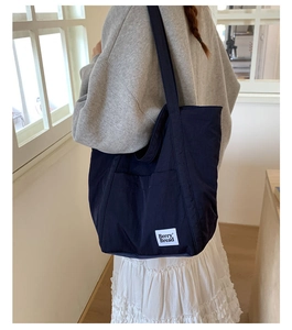 Detail showing the navy blue canvas tote bag with Berry Bread label on model's shoulder