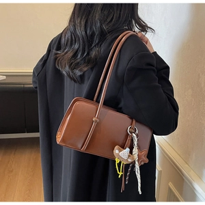 Détail du sac baguette marron en similicuir avec breloques d'ours et étoile