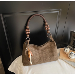 Detail of brown suede tote with letter embossing and wooden bead braided handles
