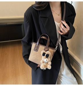Close-up van bruine emmertas met een teddybeer hanger en bruine lederen handvatten