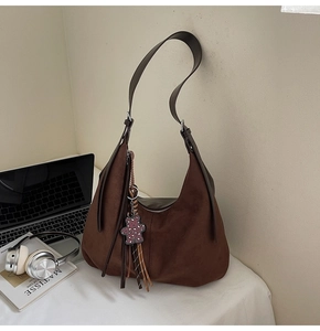Detailed macro view of brown vintage suede tote bag texture with cute bear charm and tassel