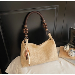 Detail of beige suede tote with wooden bead handle and debossed circular patterns