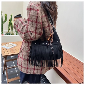 Dettaglio borsa vintage nera con frange, stelle argentate e perline in legno sulla tracolla