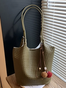 Olive green woven tote bag with shoulder straps and decorative charm for autumn