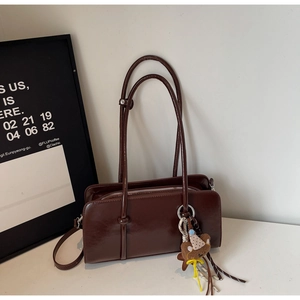 Détail du sac baguette marron vintage brillant avec un pendentif ours en peluche mignon