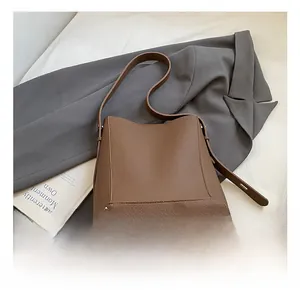 Detail showing the lychee pattern leather texture and brown bucket bag strap