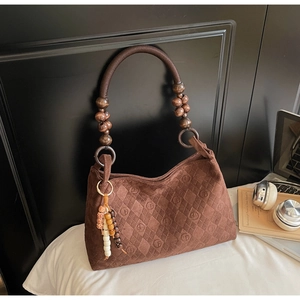 Detail of a brown suede bag with quilted logo texture and wooden beaded handles