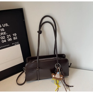 Détail du sac baguette marron foncé avec pendentif ours en peluche et fermeture éclair