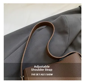 Detail shot of the adjustable leather shoulder strap on a brown pebbled leather bag
