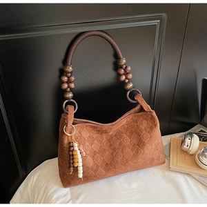 Detail view of brown suede shoulder bag with quilted logo pattern and wood bead handle