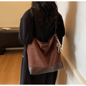 Detail of vintage brown suede tote bag featuring a reinforced base and plush charm